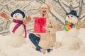 Women in winter clothes with Christmas gift. Girl and snowman on white snow background. Fashion portrait of young model Royalty Free Stock Photo