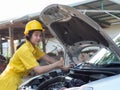 Women in work uniforms are measuring car engine oil levels