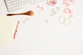 Women working space with make up blush, pink flowers, earrings over white background.