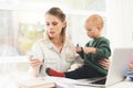 A woman works during maternity leave at home. A woman works and cares for a child at the same time. Royalty Free Stock Photo