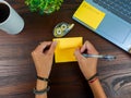 women write in yellow notes, mock up yellow notes. Women's hands write notes on yellow note paper in the office background