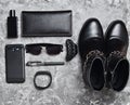 Women's boots, accessories, gadgets for a business lady layout on a concrete surface. Perfume bottle, purse, pen, smartphone