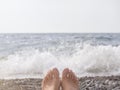 Women& x27;s feet on the background of a pebble beach and the sea