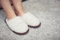 women& x27;s feet in fur Slippers on a warm carpet.