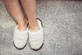 women& x27;s feet in fur Slippers on a warm carpet.
