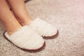 women& x27;s feet in fur Slippers on a warm carpet.