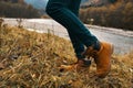 women& x27;s feet jeans shoes dry grass autumn river mountains in the distance