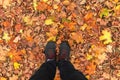 Legs in black sneakers stand on yellow autumn leaves in the park. Autumn concept Royalty Free Stock Photo