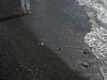 Women& x27;s feet standing on shallow wet sea pebbles near frothy water Royalty Free Stock Photo