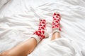 women& x27;s feet in warm socks with red hearts on a white bed Royalty Free Stock Photo