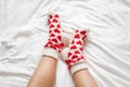 women& x27;s feet in warm socks with red hearts on a white bed Royalty Free Stock Photo