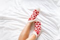 women& x27;s feet in warm socks with red hearts on a white bed Royalty Free Stock Photo