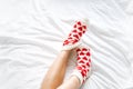 women& x27;s feet in warm socks with red hearts on a white bed Royalty Free Stock Photo