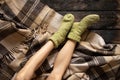 women's feet in warm socks on a woolen plaid plaid on the floor, feet on the floor at home, home Royalty Free Stock Photo