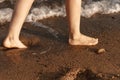 women& x27;s feet washed by a wave walk on a sandy beach. Royalty Free Stock Photo