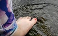 Women& x27;s foot with colorful leggings and red nail polish sitting in water during a rain storm