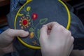 Women's hand embroidery in a hoop, a woman embroider a pattern on dark material. Close-up. The concept of needlework, hobby,