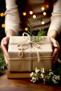 Women& x27;s hands is carefully decorating a gift box in craft paper with rope and flowers. Christmas and zero waste