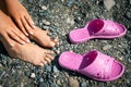 Women& x27;s hands and feet and rubber slippers on the background of stones on the beach. Rocky pebble beach on the Black