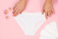 Women& x27;s hands with beautiful panties and sanitary pads on pink background