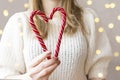 women& x27;s hands holding red candy in the form of heart. Sweets in the hands of a woman in a white knitted sweater. Royalty Free Stock Photo