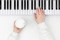 Pianists hands playing piano with a cup of coffee on a white background.