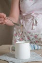 women& x27;s hands pour vegetable oil from a teaspoon into a mug at studio