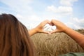 Women& x27;s hands in the shape of a heart on the background of the sky and a field with ears of corn. Hands in the shape of Royalty Free Stock Photo