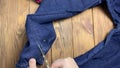 Women's hands unpick seam with scissors on jeans.