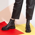 Women& x27;s legs in black pants and black short shoes on medium heel stands in the studio against a colored background Royalty Free Stock Photo