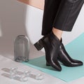 Women& x27;s legs in black pants and black short shoes on medium heel stands in the studio against a colored background Royalty Free Stock Photo