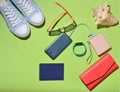 Women's trendy travel accessories and technology gadgets on the green surface. Sneakers, passport, purse, glasses, smartphone Royalty Free Stock Photo