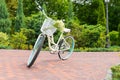 Womens white bicycle on the footpath with a bouquet in a basket