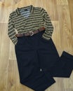 Women yellow checked shirt and black pants with brown belt placed on wooden like background, casual style