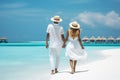 A women yellow swimming costume and with hats walks down a tropical beach with turquoise sea in the Maldives islands Royalty Free Stock Photo