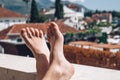 Womens beautiful bare feet on a sunny terrace overlooking the city