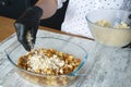 Womens black-gloved hands make apple crisp pie, put dough crumbs on grated apple