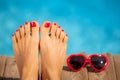 Womens feet with red pedicure against blue water background Royalty Free Stock Photo