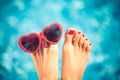 Womens feet with red pedicure against blue water background Royalty Free Stock Photo