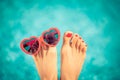 Womens feet with red pedicure against blue water background Royalty Free Stock Photo