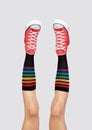 Womens legs in stylish red sneakers and rainbow socks on gray background Royalty Free Stock Photo