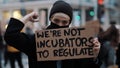 Womens march. Young woman with face mask holding banner sign - We are not incubators to regulate. protest against strict