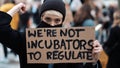 Womens march. Young woman with face mask holding banner sign - We are not incubators to regulate. protest against strict