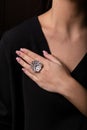 Womens silver ring in the form of a big flower with diamonds on the finger, on a black background. Royalty Free Stock Photo