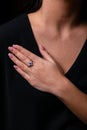 Womens silver ring in the shape of a flower with red stone in the middle on finger, on a black background. Royalty Free Stock Photo