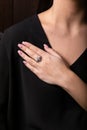 Womens silver ring wth diamonds and flower on the finger, on a black background. Royalty Free Stock Photo