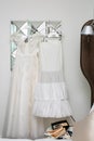 Womens white dress with patterns in the shape of flowers hanging on a hanger,womens ballet flats on the coffee table.