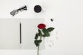 Womens working space with cup of coffee, pencil, empty notebook, glasses and rose flower on white table top view. Flat lay styling Royalty Free Stock Photo