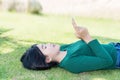Womwen girl lying on the lawn with smartphone