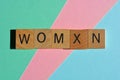 Womxn, word in wooden alphabet letters isolated on pastel background